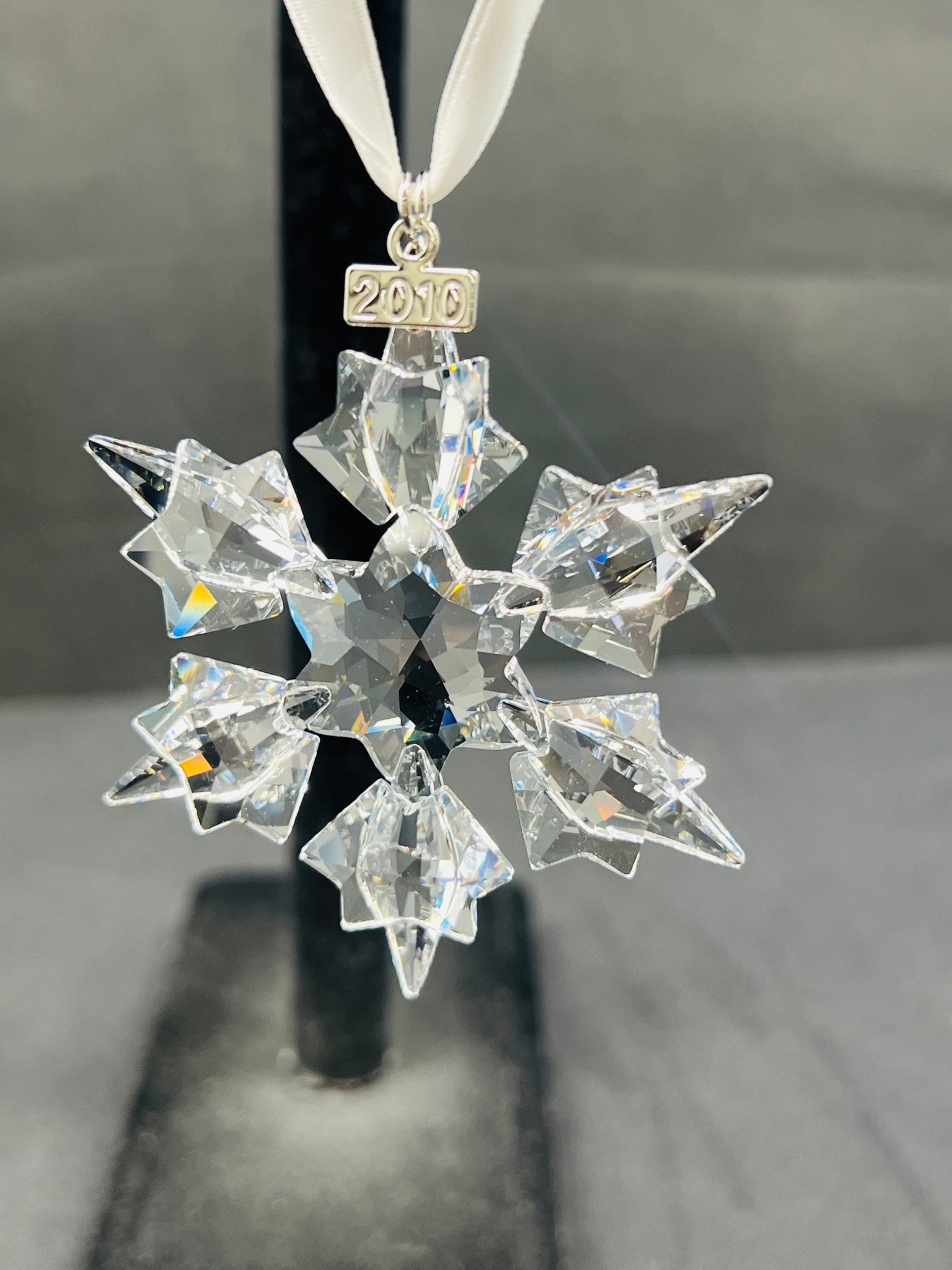 Crystal snowflake ornament with '2016' on a white ribbon against a gray background