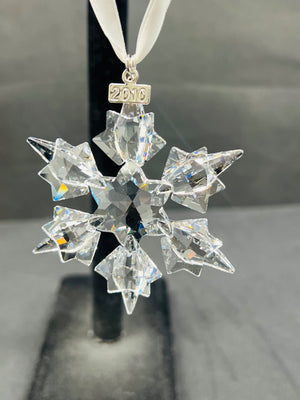 Crystal snowflake ornament with '2016' on a white ribbon against a gray background