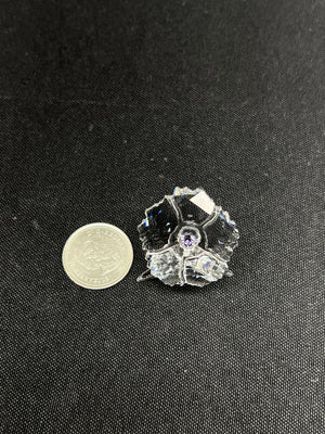 Small decorative item next to a coin on a dark fabric background