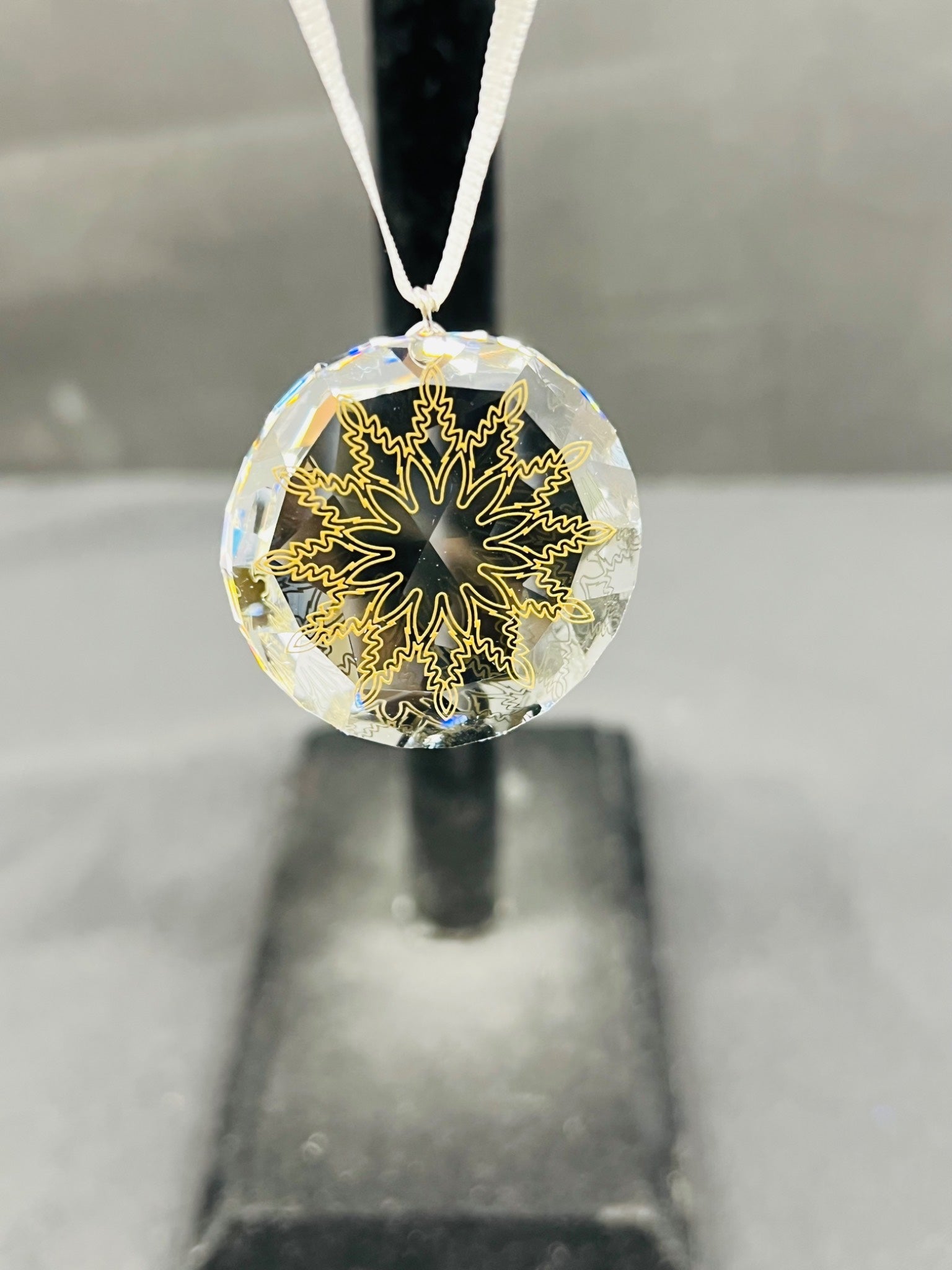 Crystal pendant with gold snowflake design on a gray background