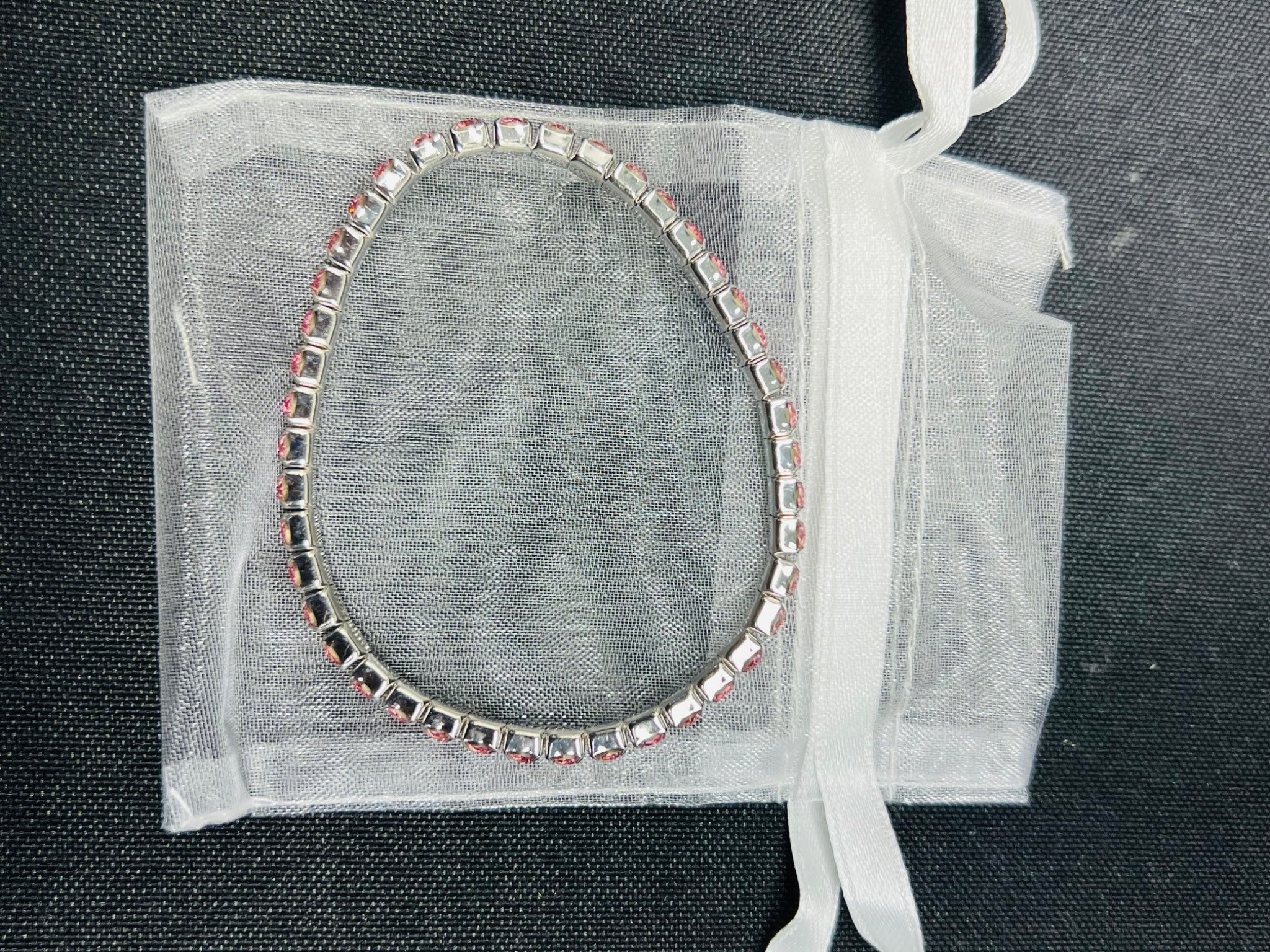 Bracelet with clear stones on a sheer white bag against a dark background