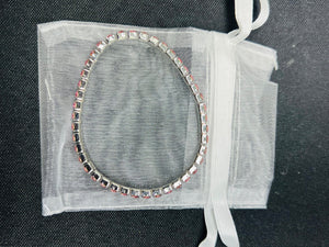Bracelet with clear stones on a sheer white bag against a dark background
