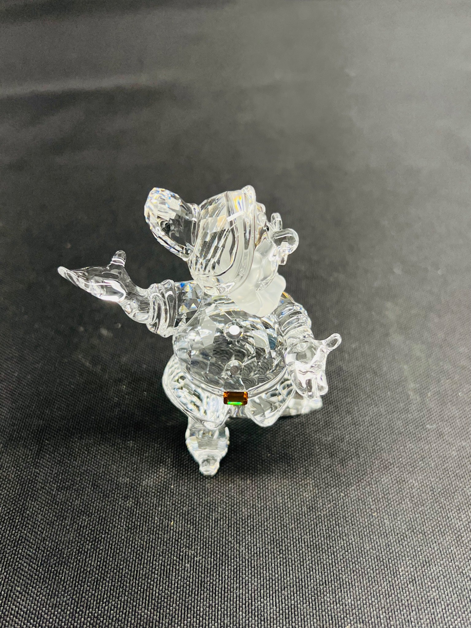 Clear glass figurine of a dog on a dark fabric background