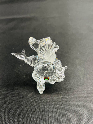 Clear glass figurine of a dog on a dark fabric background