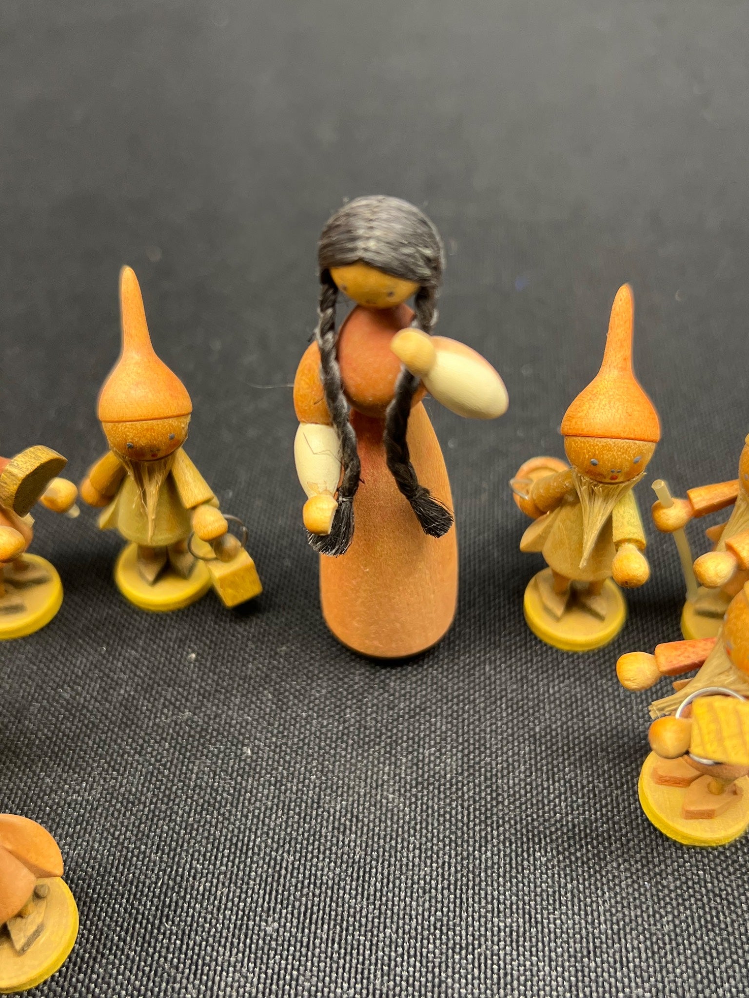 Small figurines with a central figure and others around on a dark background