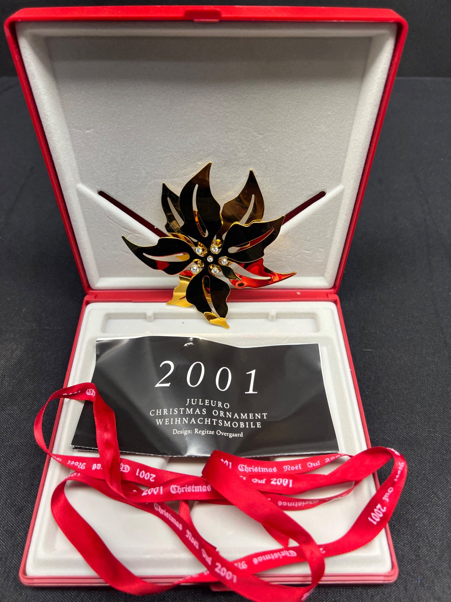 Christmas ornament with '2001' tag in an open red box on a black background