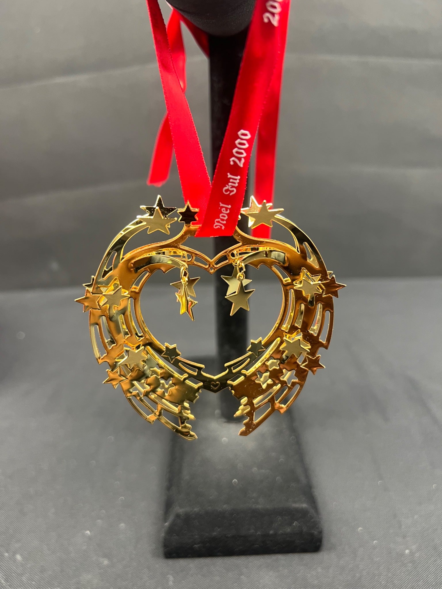 Gold star-shaped ornament on a stand with a red ribbon