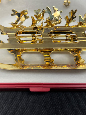 Gold decorative item with intricate designs on a black surface