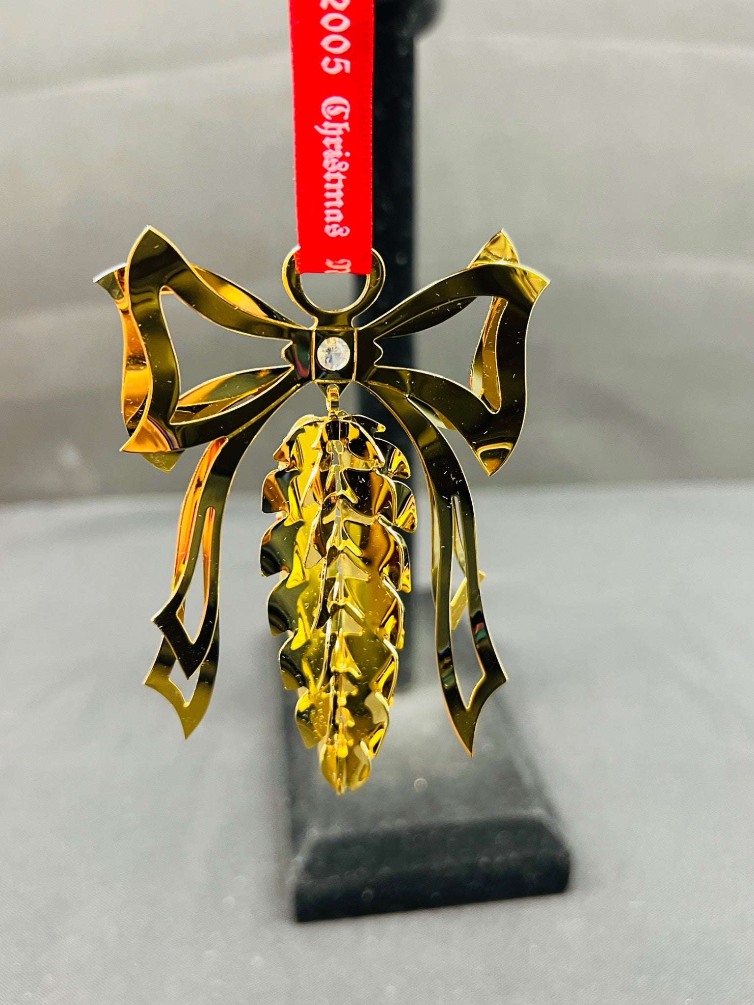 Gold bow-shaped ornament with red ribbon on a gray background