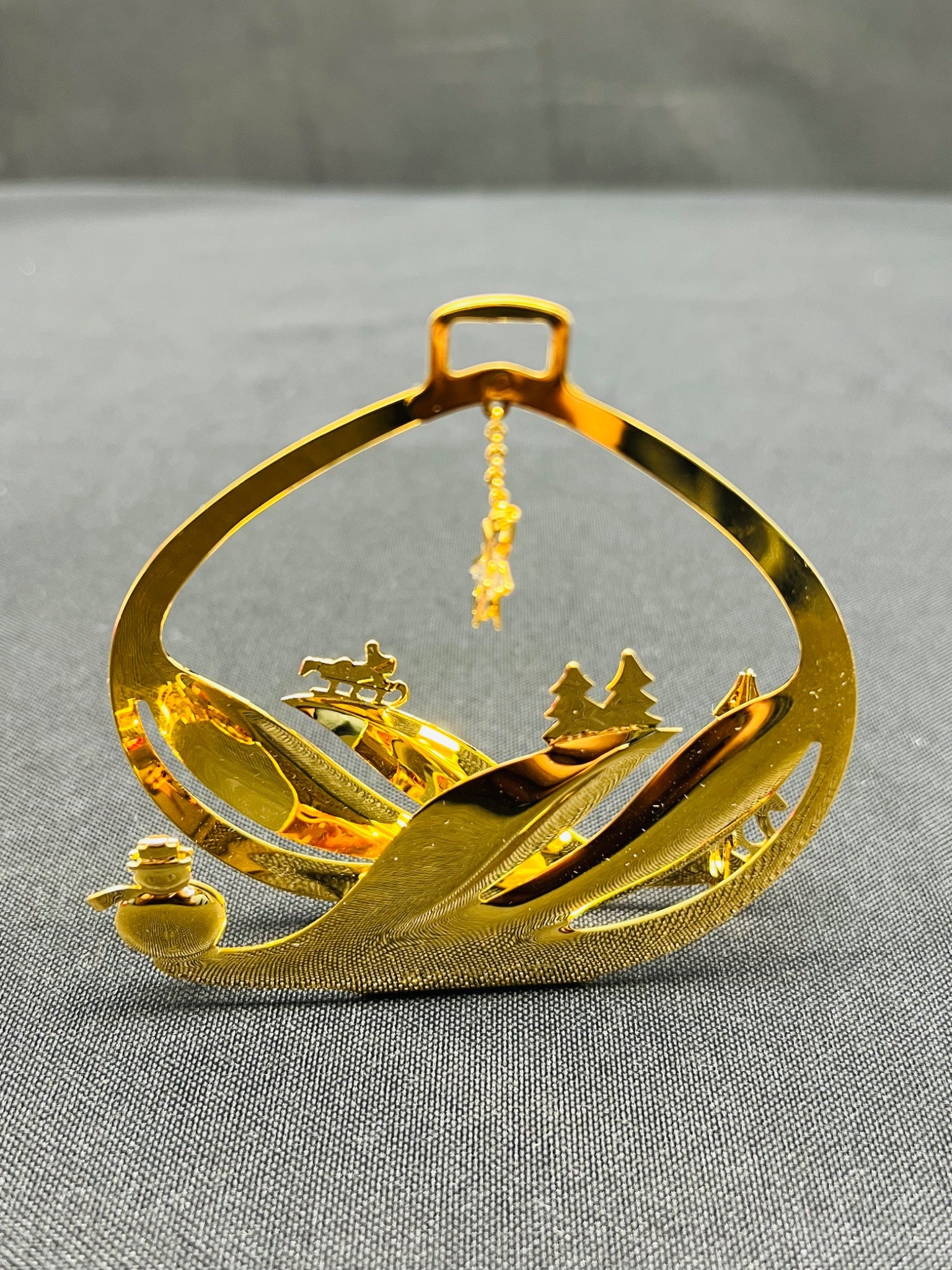 Gold decorative item with a scenic design on a gray surface