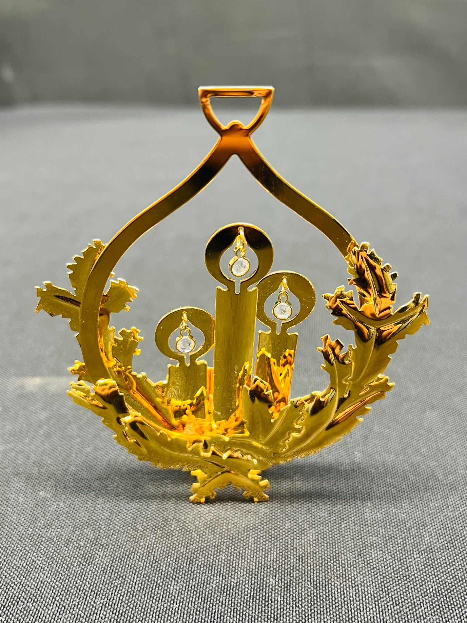 Gold decorative item with intricate designs on a gray surface