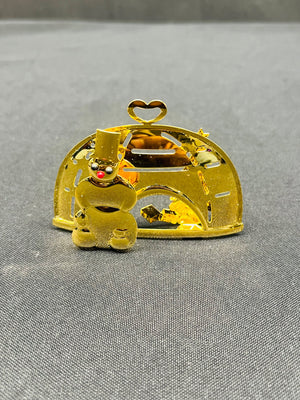 Gold-colored decorative item with a small figure inside on a gray surface