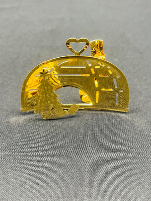 Gold-colored decorative item with a heart design on a gray background