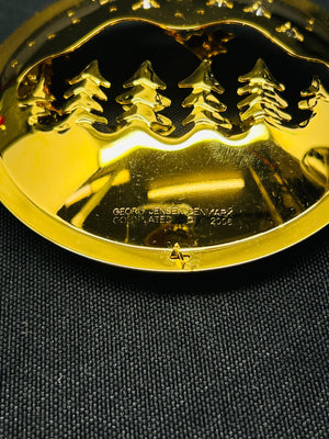 Gold-colored decorative item with a design on a dark fabric background