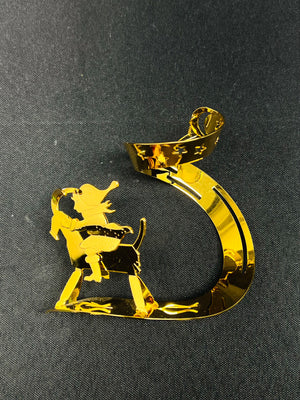 Gold decorative item shaped like a number '5' with a silhouette of a person on a horse against a black background