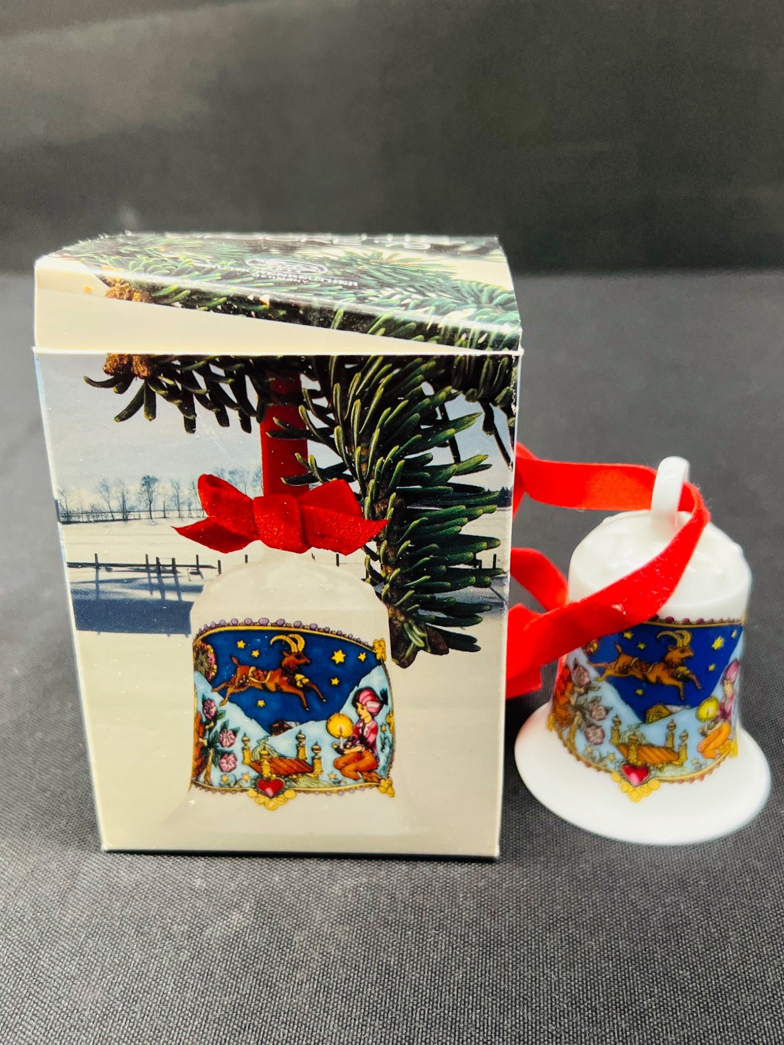 Decorative Christmas bell ornament with packaging on a gray background