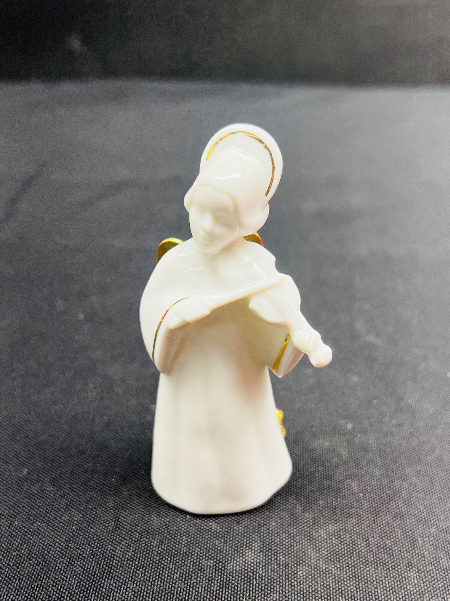 White angel figurine with gold accents on a dark fabric background