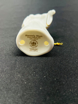 Back view of a white violin ornament with engraved text on a gray fabric background