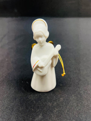 White angel figurine holding a guitar on a dark fabric background