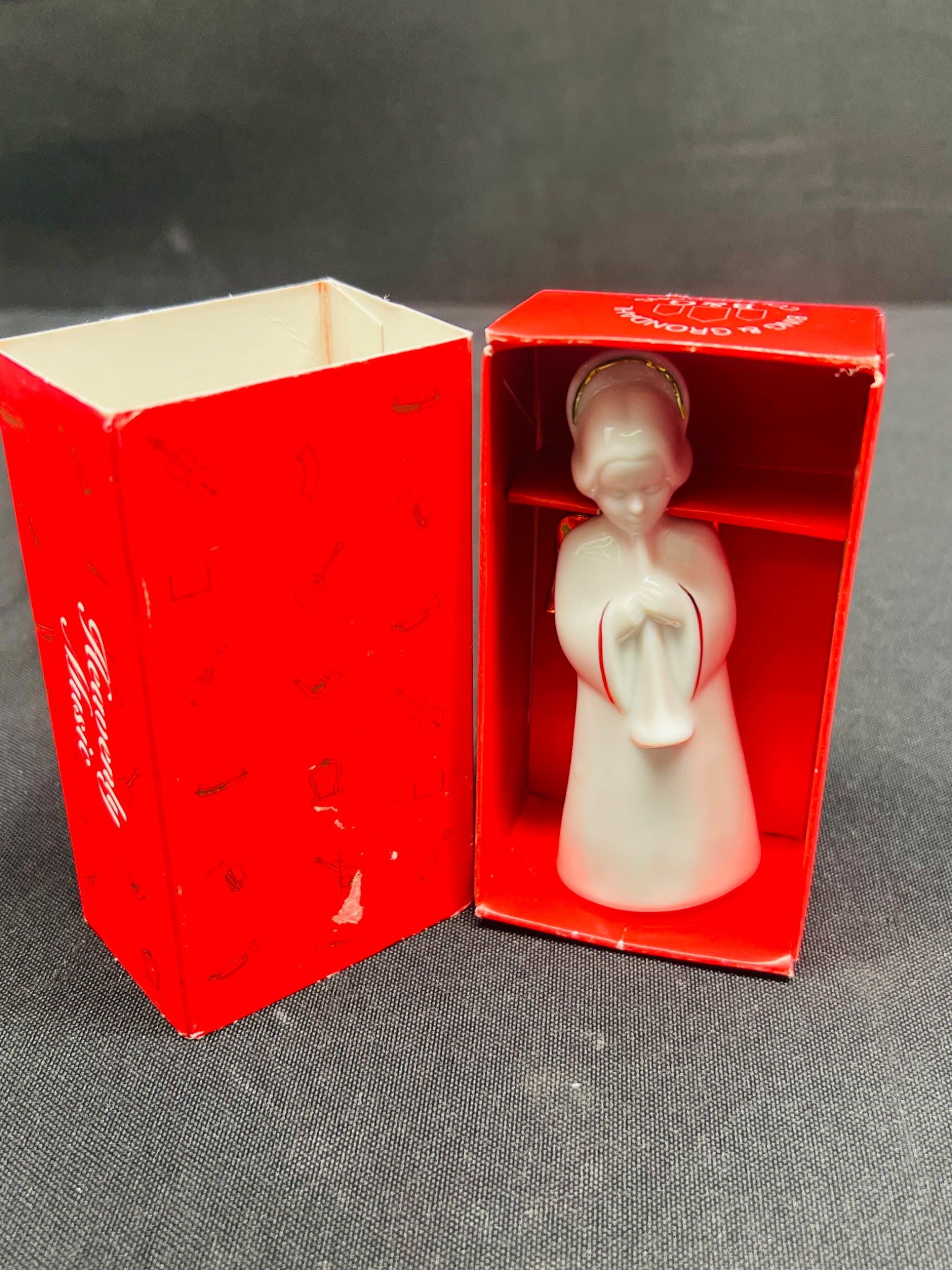 Small white angel figurine in a red box with 'Festive' branding on a gray surface.