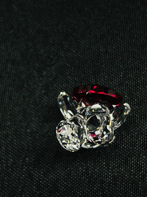Ring with red gemstone and clear crystals on a black background