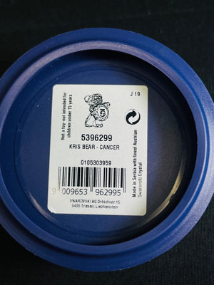 Close-up of a blue container lid with a label featuring a bear illustration and text.