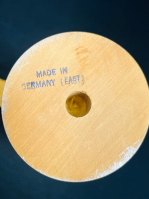 Wooden object with 'Made in Germany (East)' engraving on a dark background