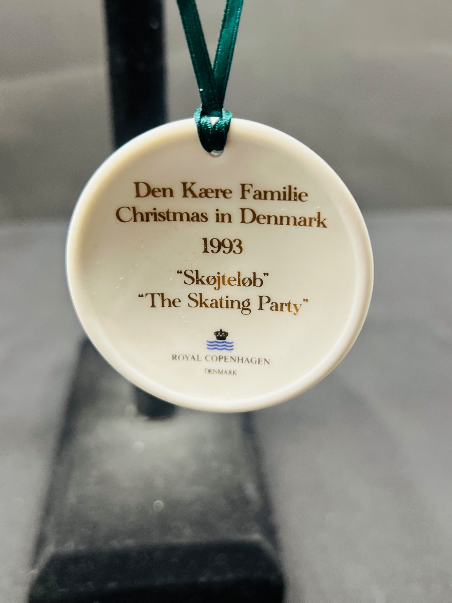 Round ceramic ornament with text and Royal Copenhagen logo on a plain background