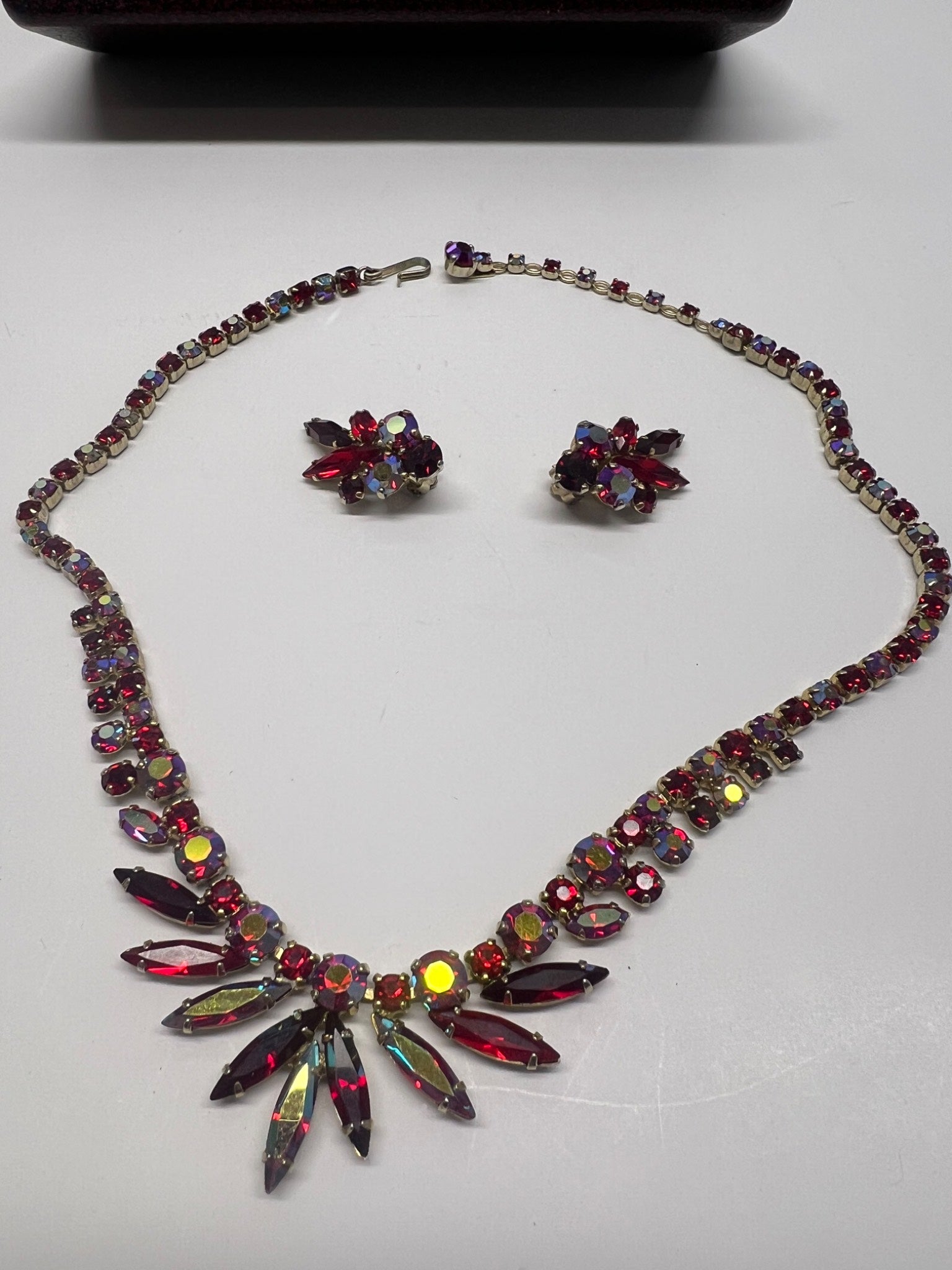 Necklace and earrings with multicolored gemstones on a light gray background