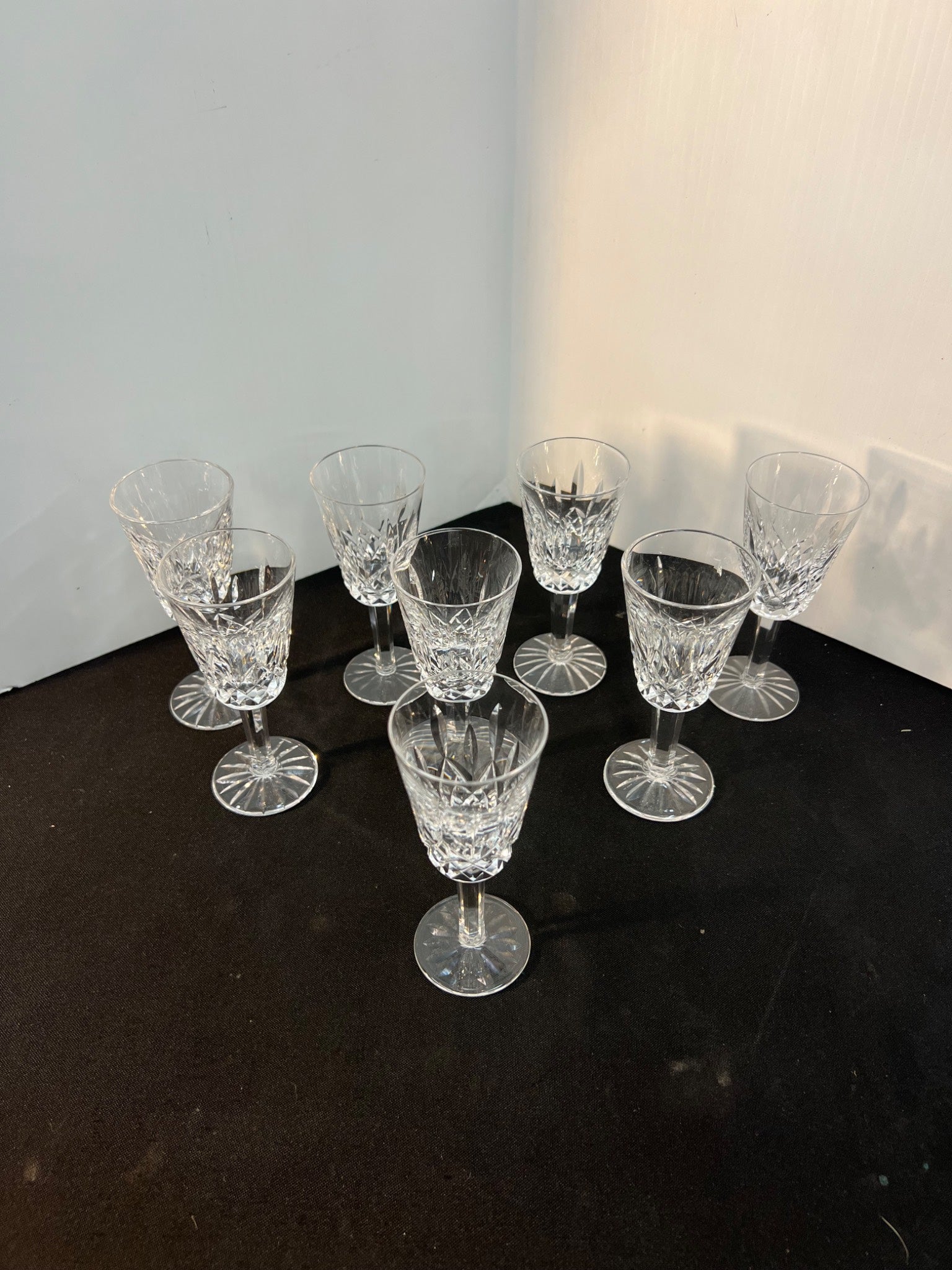 Set of crystal glasses on a dark surface with a white wall background