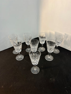 Set of crystal glasses on a dark surface with a white wall background