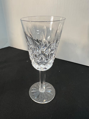 Clear crystal wine glass on a black surface with a white background
