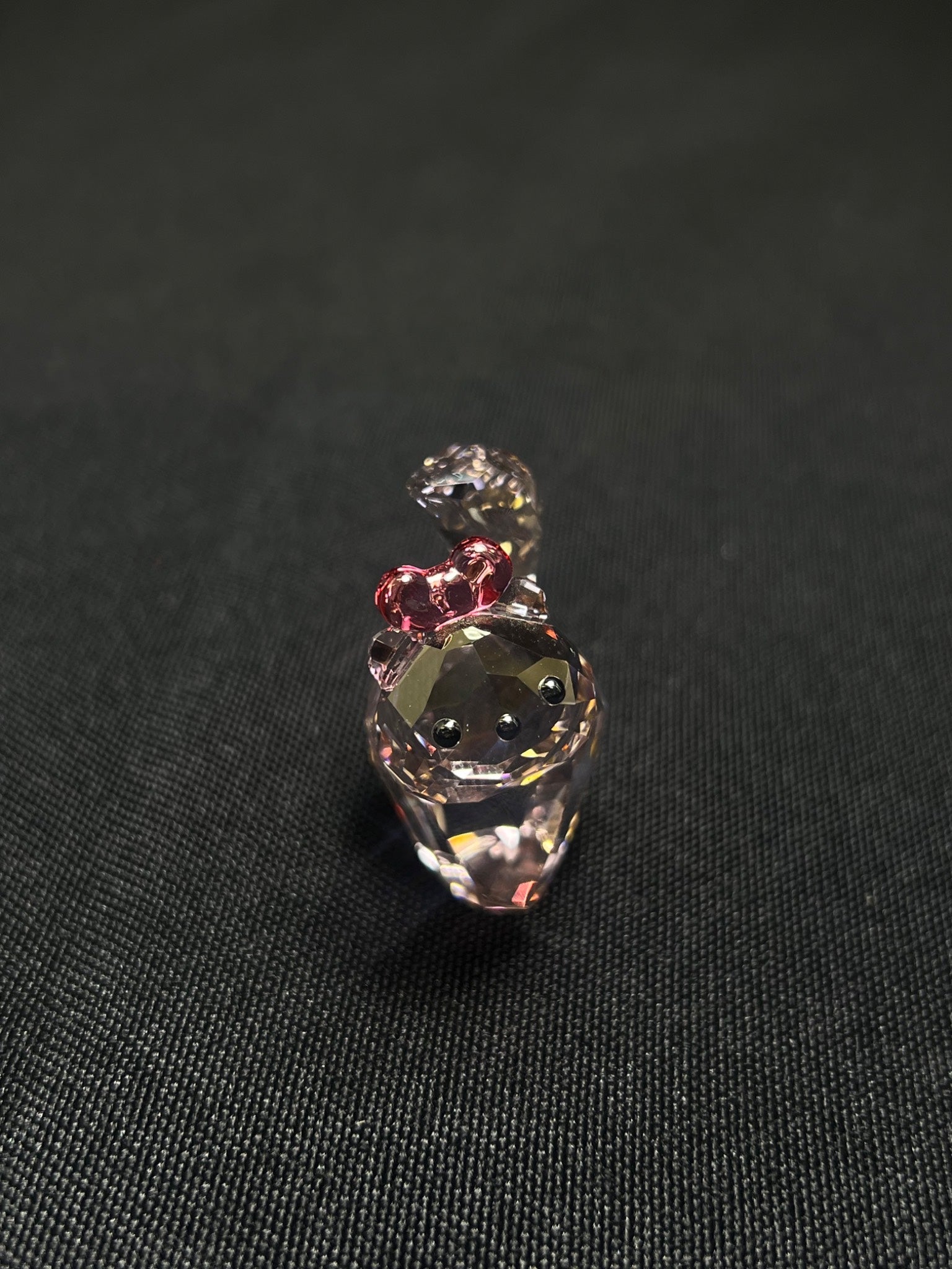 Small decorative figurine with a pink bow on a black background