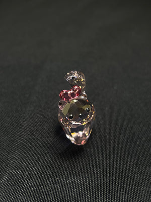 Small decorative figurine with a pink bow on a black background