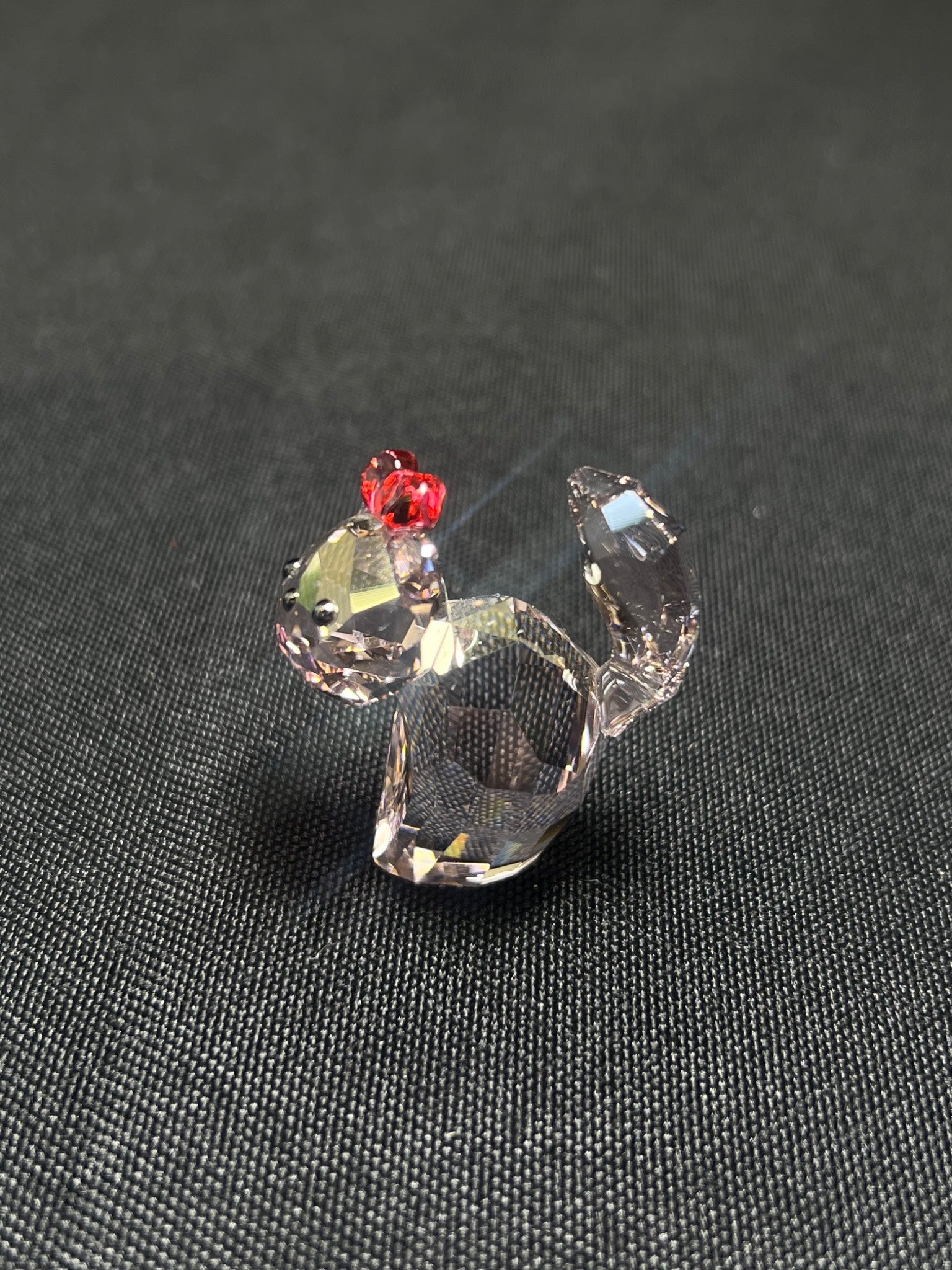 Crystal figurine of a rooster on a dark textured surface
