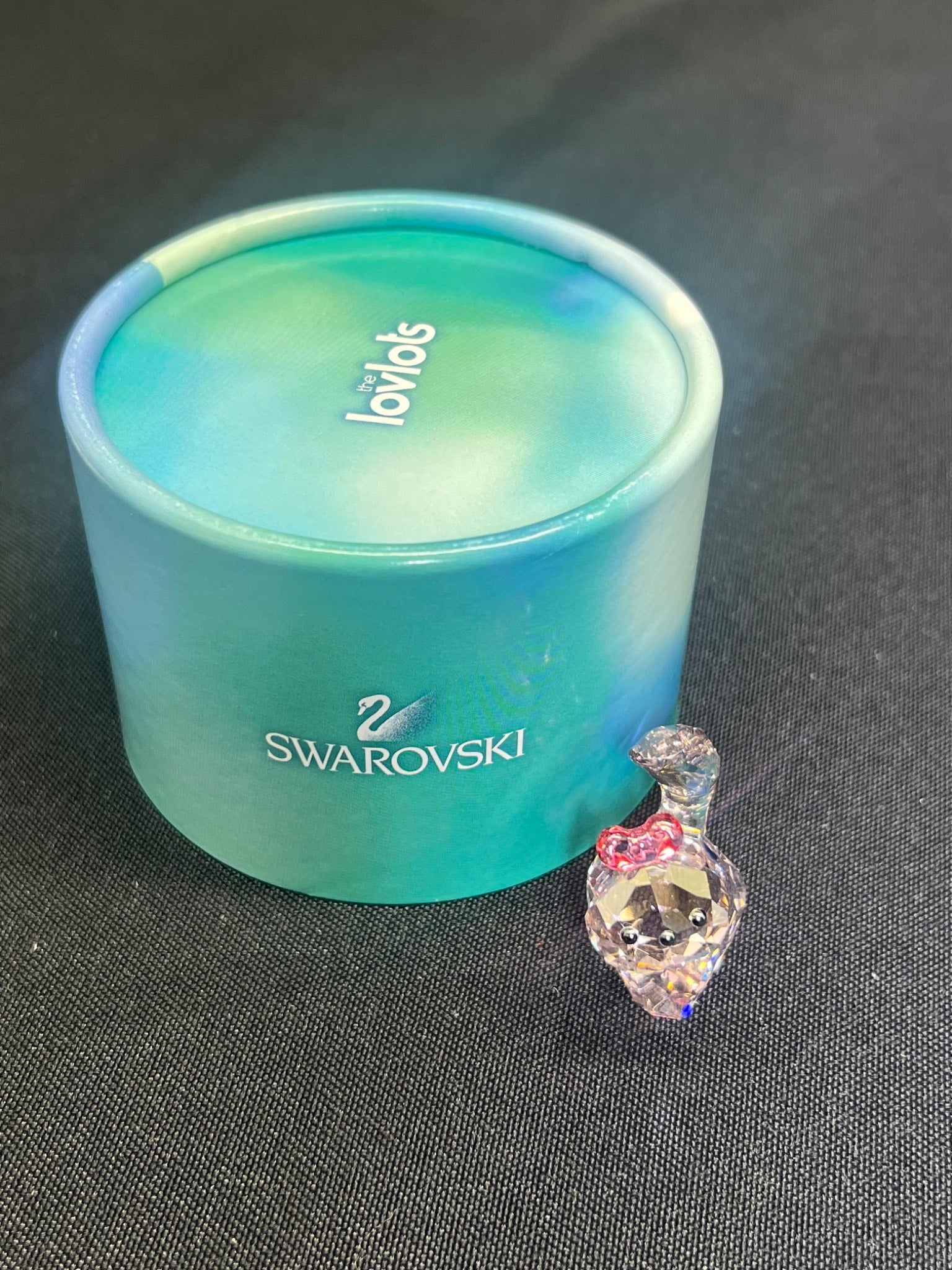 Swarovski crystal heart charm next to a blue Swarovski container on a dark surface