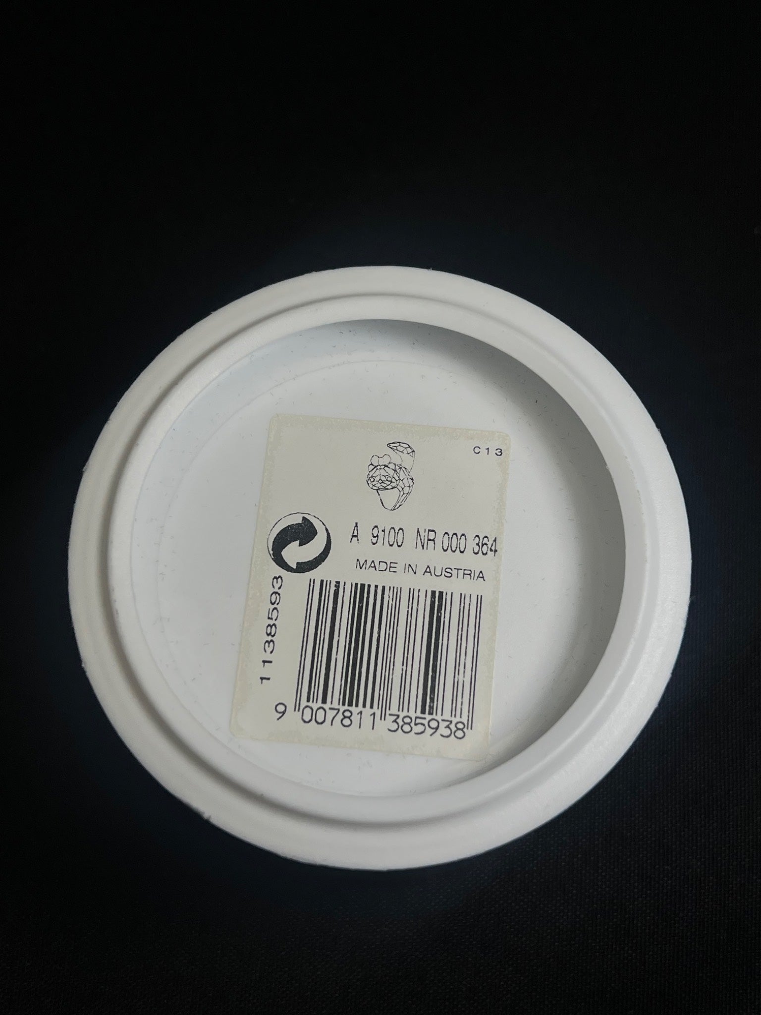 White container lid with a label and barcode on a black background