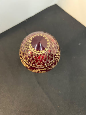 Decorative red and gold spherical object on a dark surface