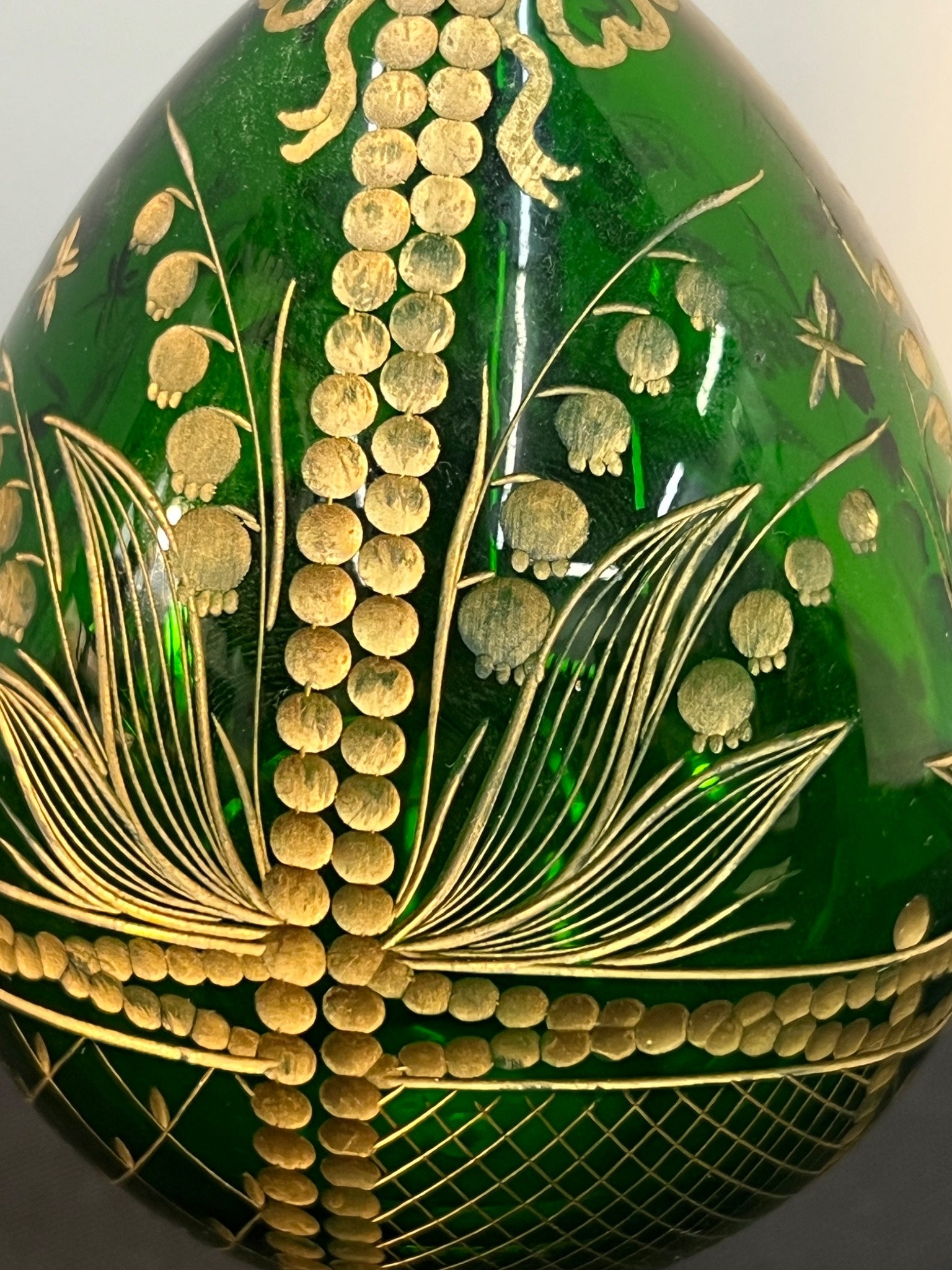 Decorative green object with gold floral patterns on a white background
