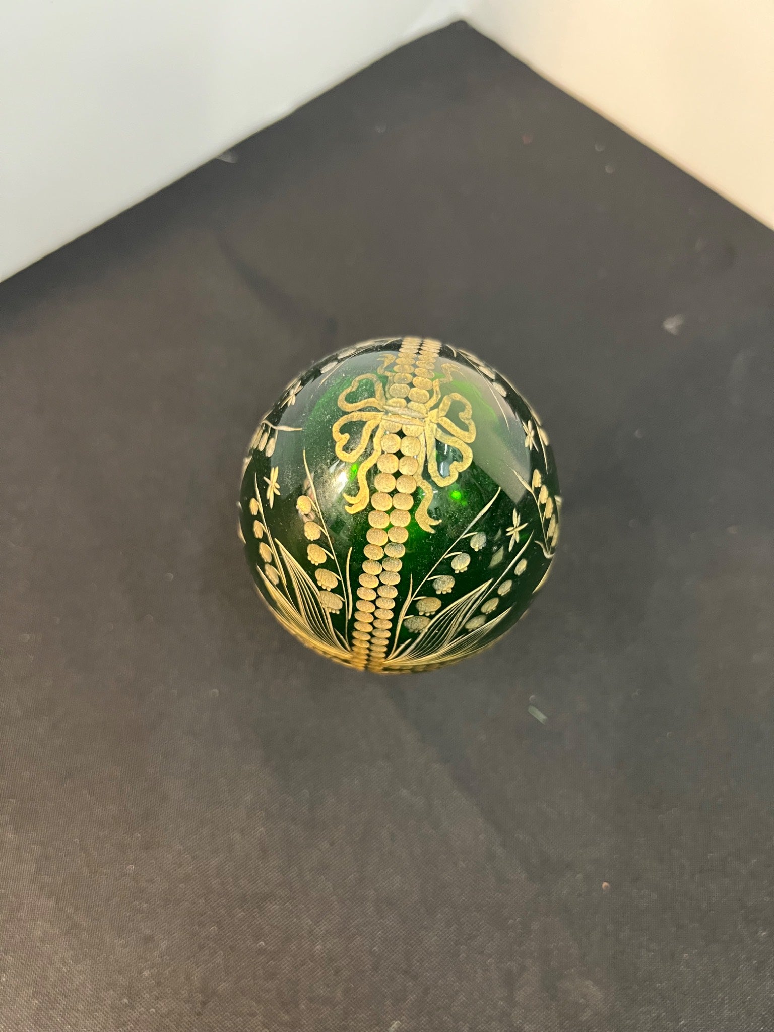 Decorative green egg with gold patterns on a black surface