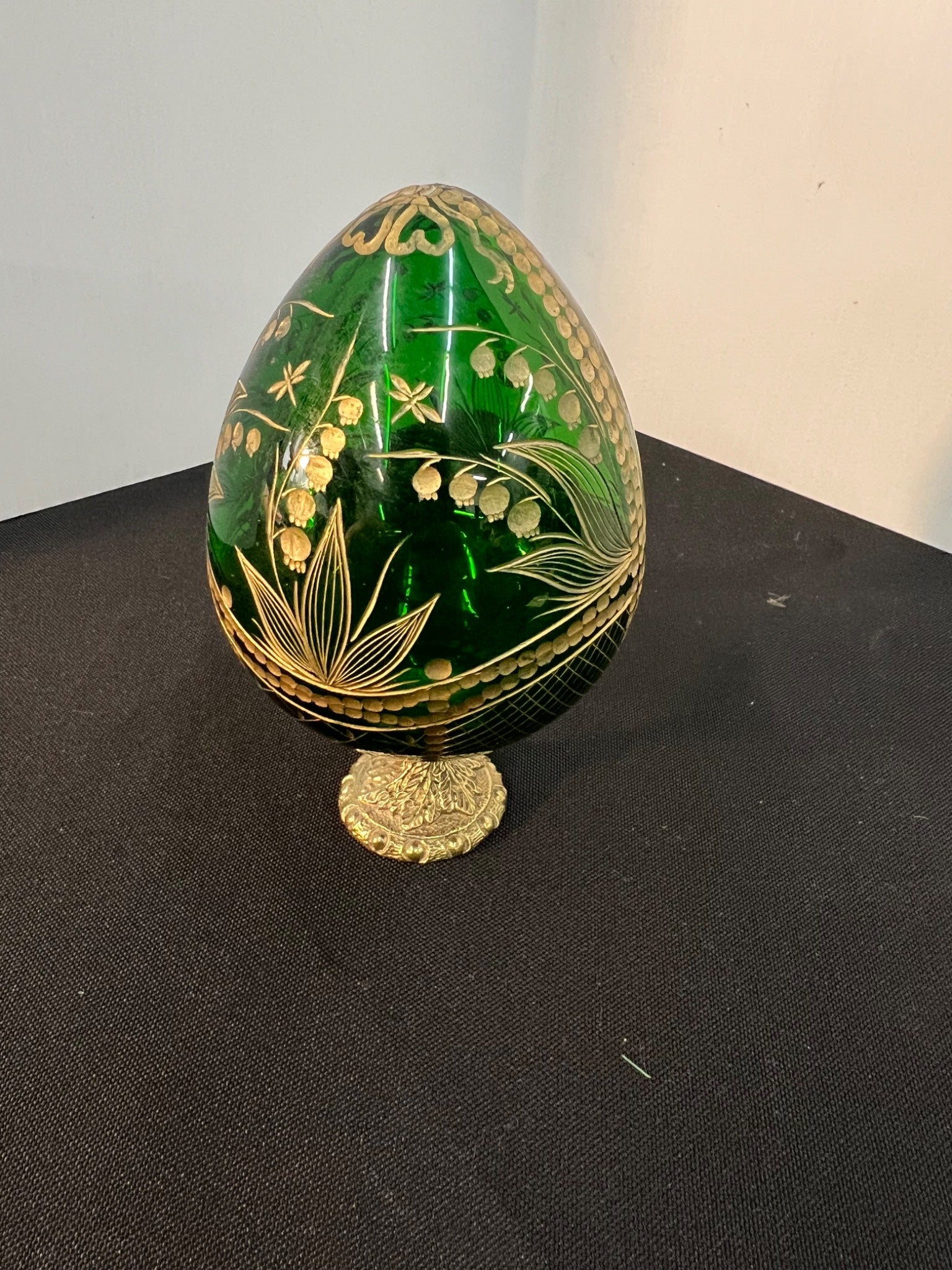 Decorative green egg with gold floral patterns on a black surface