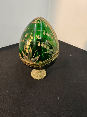 Decorative green egg with gold floral patterns on a black surface