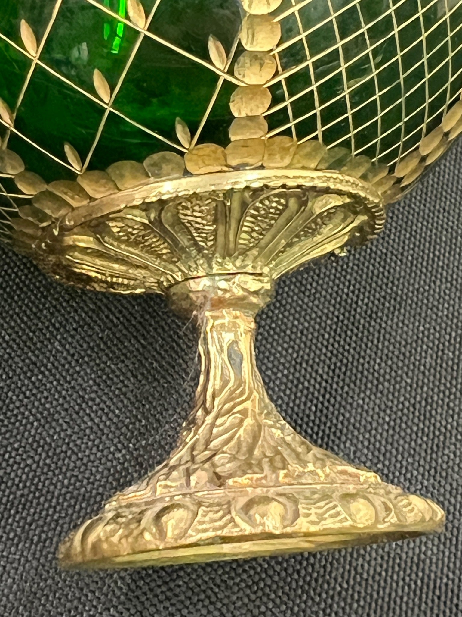 Decorative object with gold and green elements on a dark background