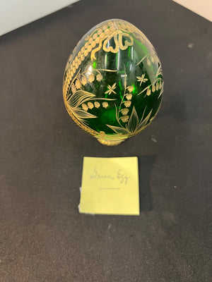 Decorative green egg with gold intricate patterns on a black surface