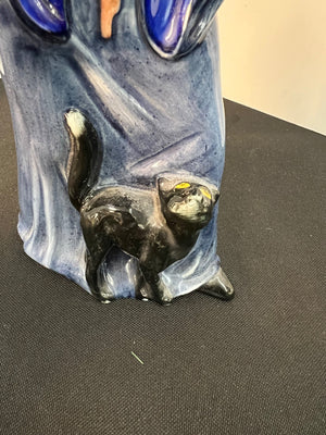 Ceramic vase with a face design on a black surface