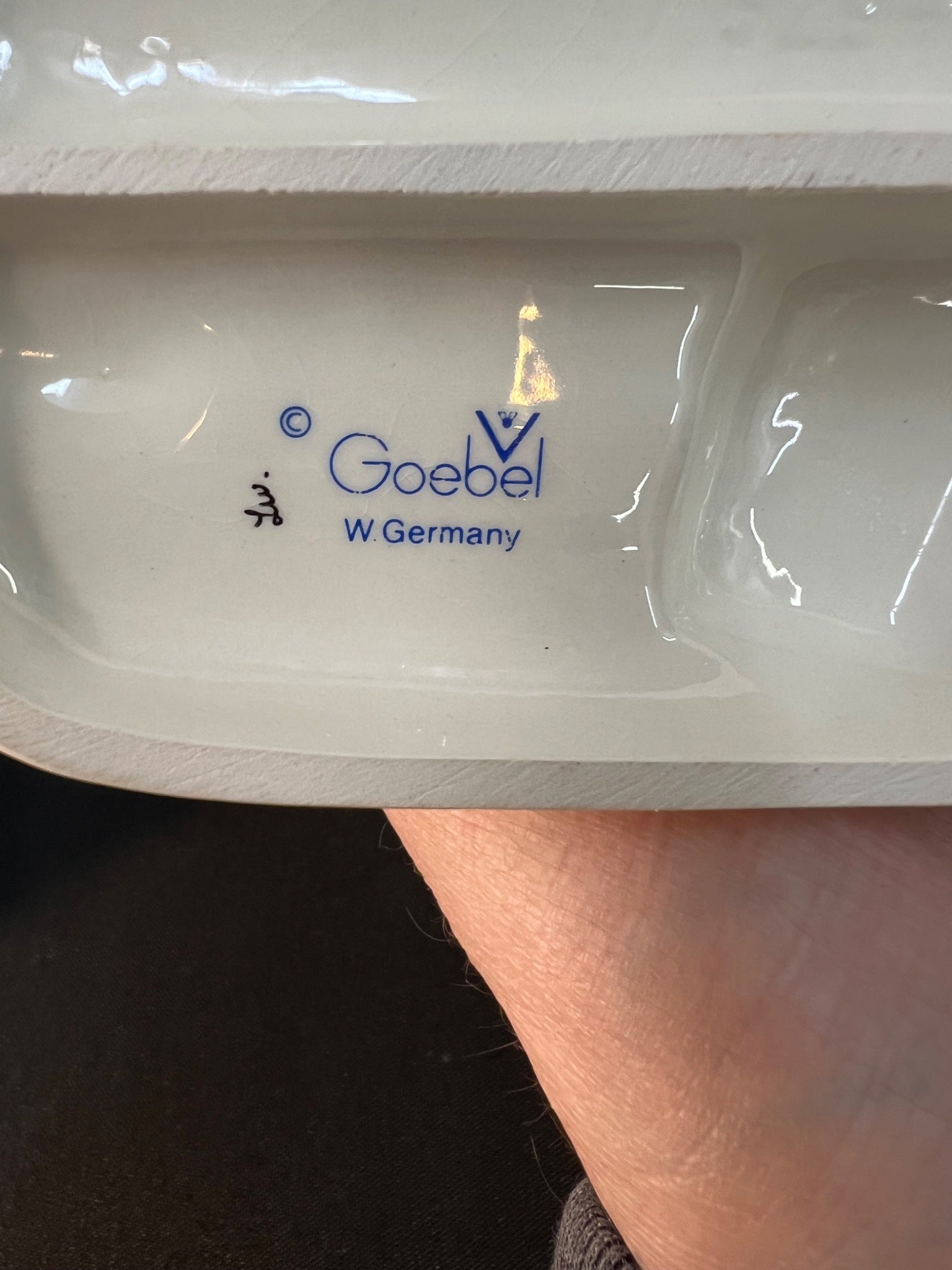 White ceramic item with 'Goebel W Germany' branding held by a hand.