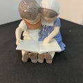 Figurine of two children reading a book on a dark surface