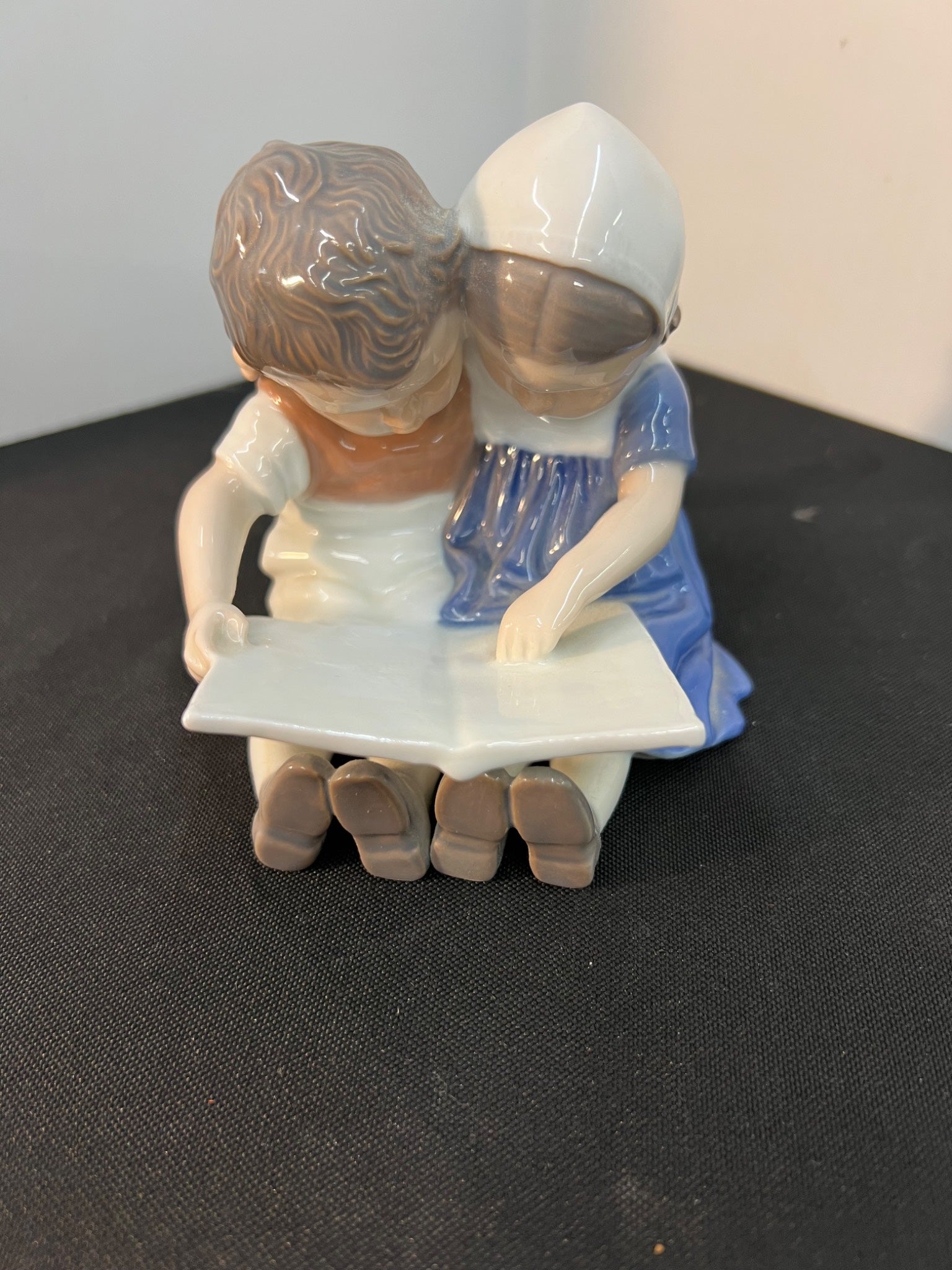 Figurine of two children reading a book on a dark surface