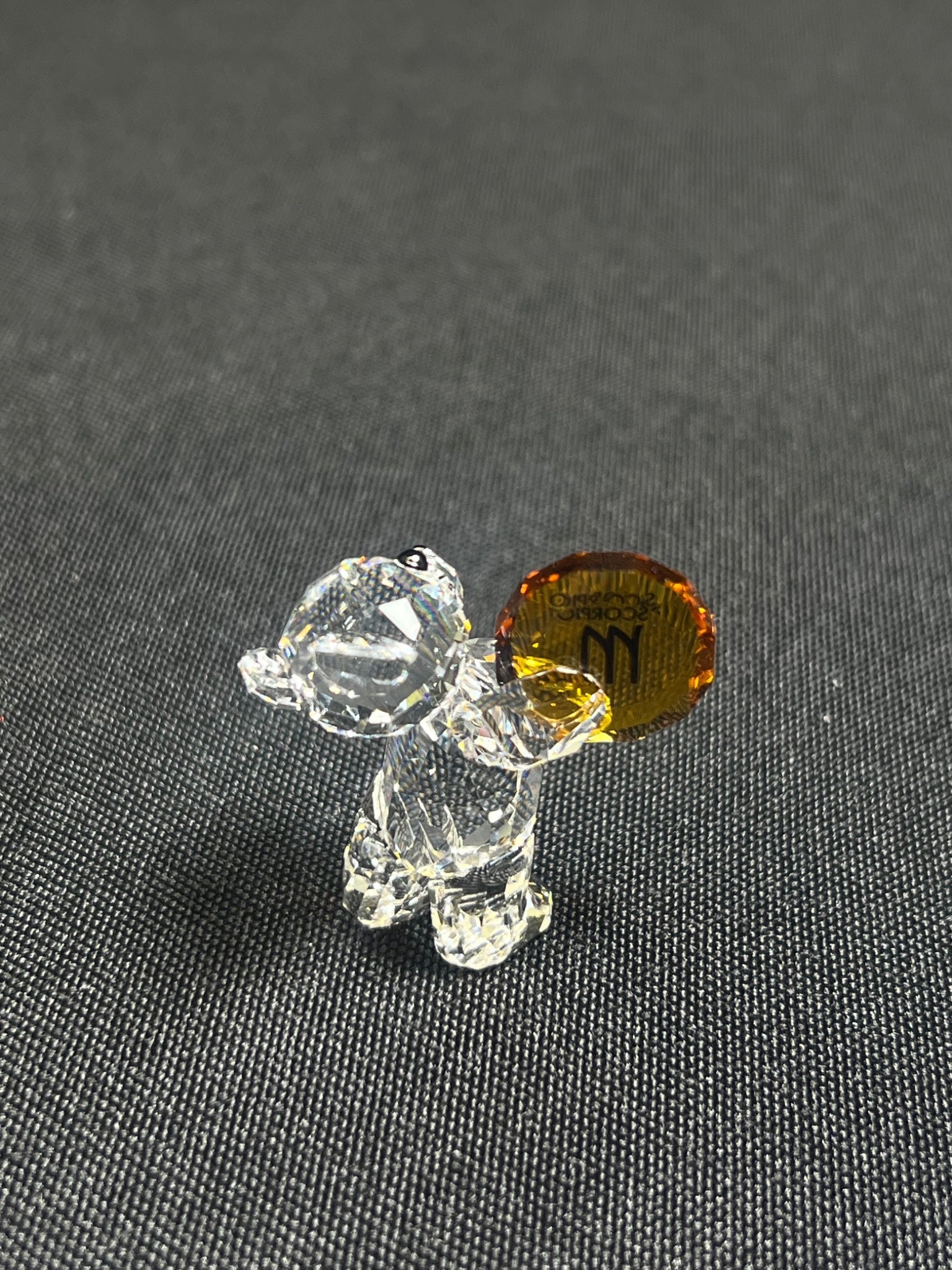 Small glass dog figurine with a brown base on a gray surface