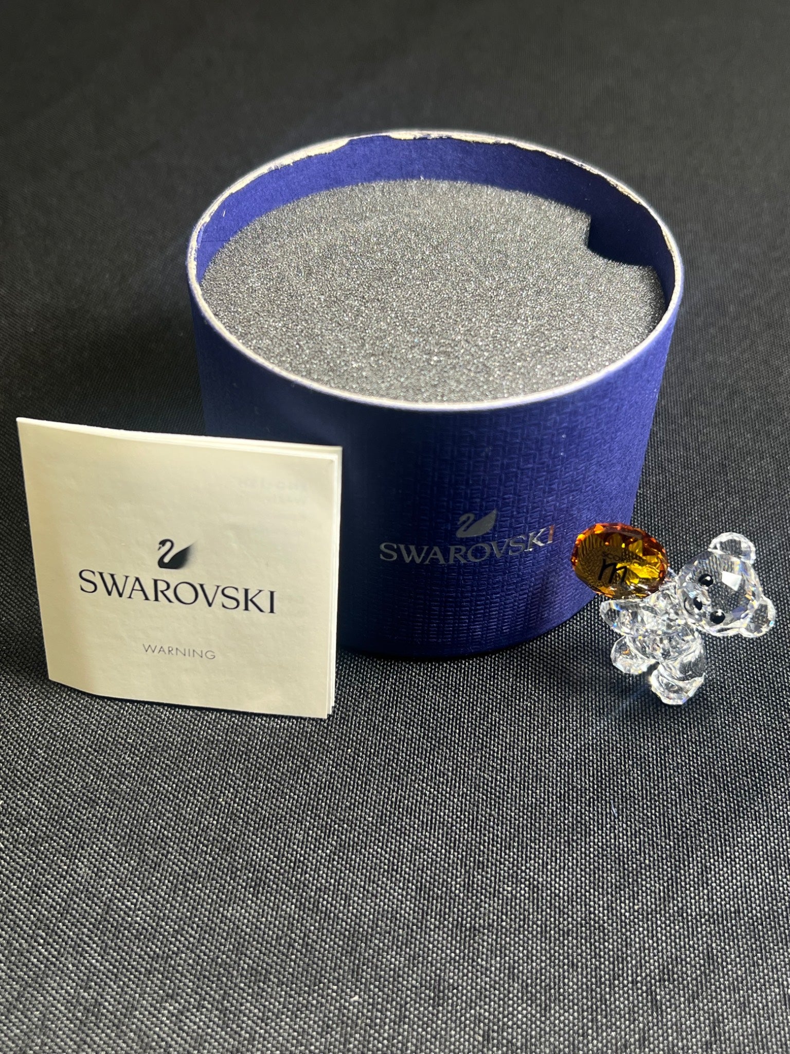 Swarovski crystal with packaging and a Swarovski branded card on a dark surface